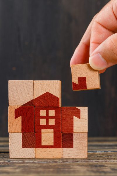 Stay at home concept on wooden background side view. hand holding wooden cube.